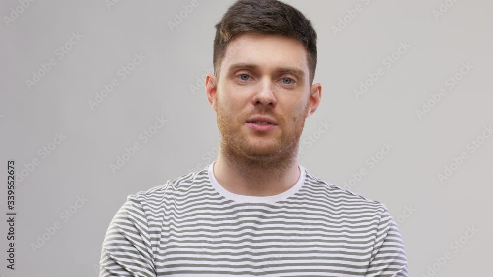 video blogging, communication and people concept - young man in striped t-shirt talking over grey background