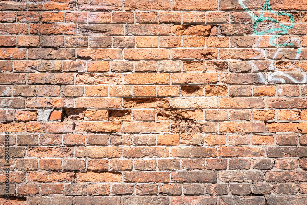 Fototapeta premium Eine alte verwitterte rotbraune Backsteinmauer mit Graffiti