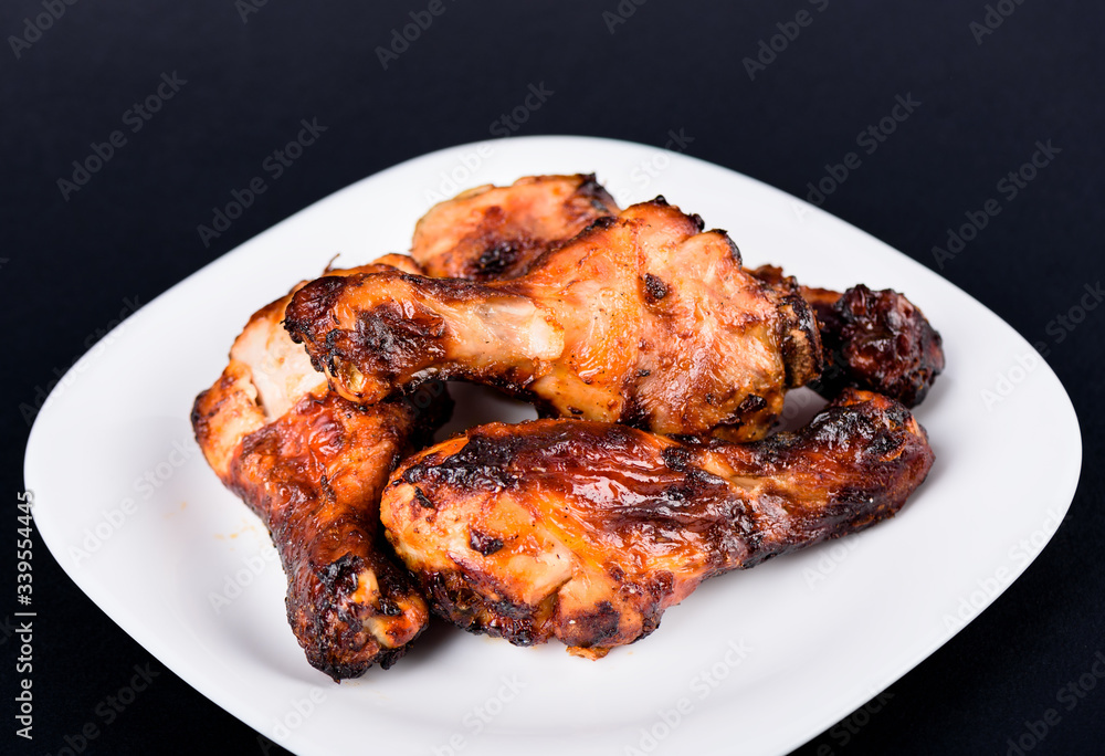 Dark background. Juicy grilled chicken drumsticks marinated in soy sauce. Dark background. Juicy grilled chicken drumsticks marinated in soy sauce.