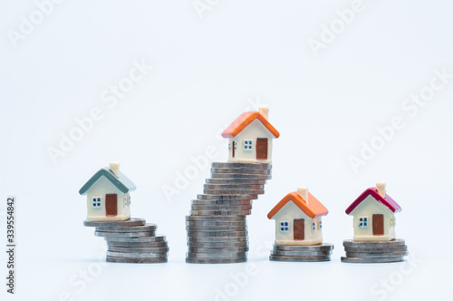 Mini house on stack of coins on white background. Concept of Investment property and Risk Management.