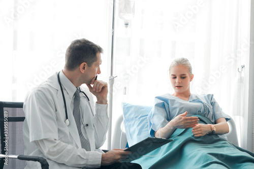 Doctor doing a physical examination of the young beautiful patient and explaining health problems to the patient who lying on the hospital bed, health care and hospital concept