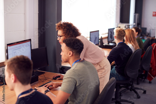 Group Of College Students With Tutor Studying Computer Design Sitting At Monitors In Classroom photo