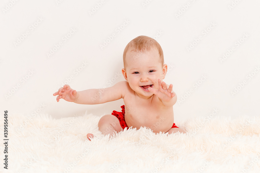 a Caucasian cheerful baby crawls on the bed on a fluffy blanket at home . an infant under one year old. pulls the handles forward. a Caucasian cheerful baby crawls on the bed on a fluffy blanket at home . an infant under one year old. pulls the handles forward.