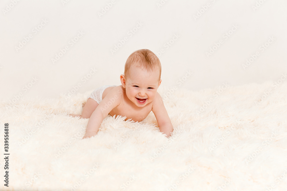 a naked Caucasian eight-month-old baby crawls on a bed on a white background . children under one year old a naked Caucasian eight-month-old baby crawls on a bed on a white background . children under one year old