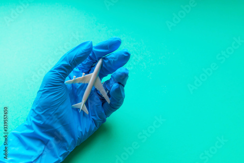 Avoid nonessential travel - concept. White airplane on a hand in a blue protective glove. top view, copy space photo