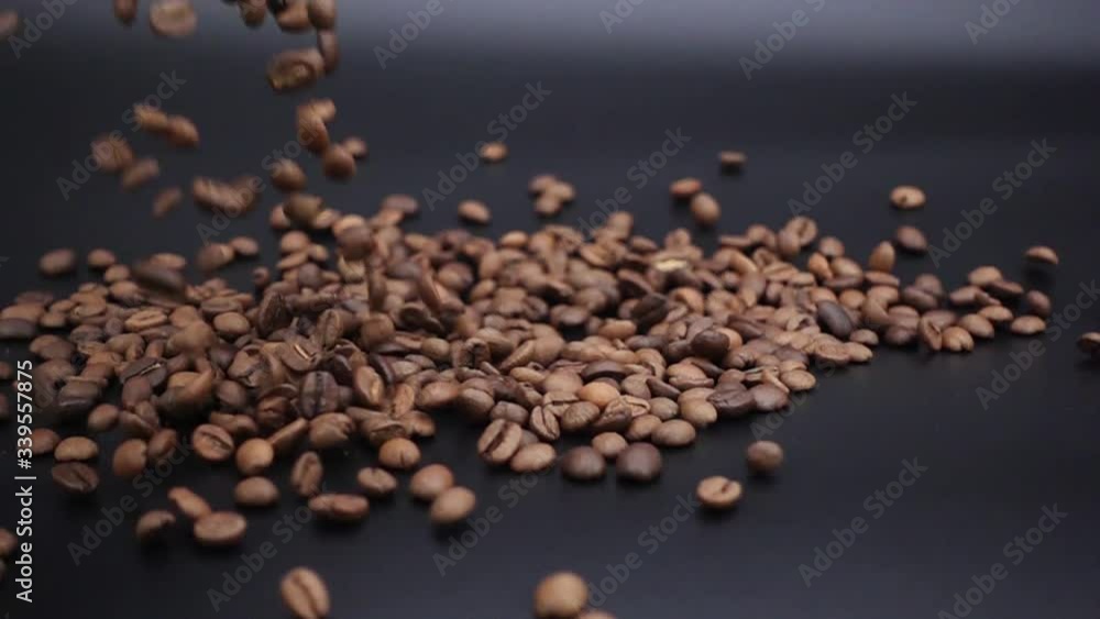 Coffee beans are poured out on a black surface. Coffee beans are poured out on a black surface.