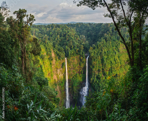 Amazing high waterfall in the depths of the jungle, a double stream falls into a deep gorge. Laos. Bolaven Plateau