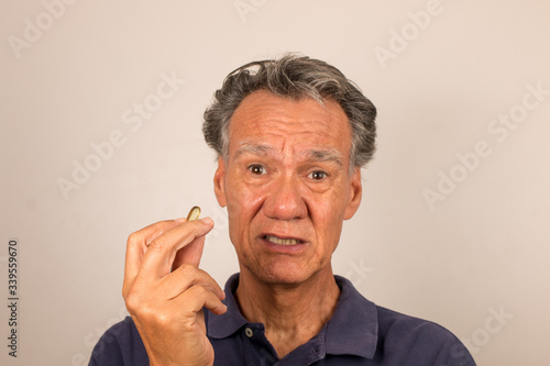 Senior Man Holding Vitamins/Medication in his hand contemplating whether to take them
