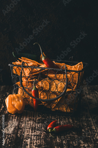 Basket with spicy nachos chips on a wooden table