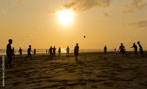 Young people playing soccer (football) on the Pangandaran beach at sunset