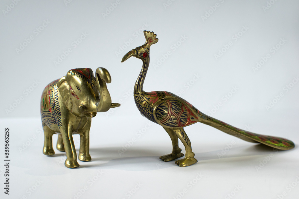 Obraz premium Small Golden Statues of Elephant and Peacock on White Background
