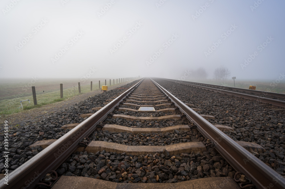 Fototapeta premium Empty railroadtracks disapearing into the spring fog.
