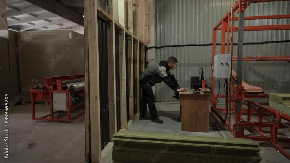 A male worker adjusts the operation of a large machine that cuts out a certain form of insulation for pipes A male worker adjusts the operation of a large machine that cuts out a certain form of insulation for pipes