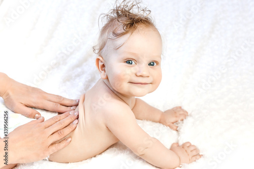 six-month-old baby receiving a back massage from a female masseur