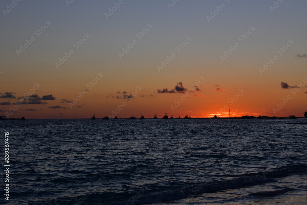 Sunrise slowly rising over the sea with fishing boats standing on the horizon Sunrise slowly rising over the sea with fishing boats standing on the horizon