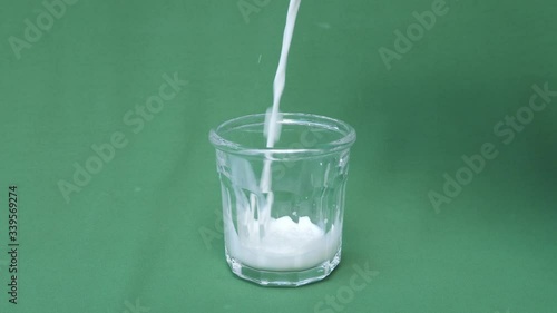 Pouring fresh milk in slow motion into a transparent glass with a green screen background