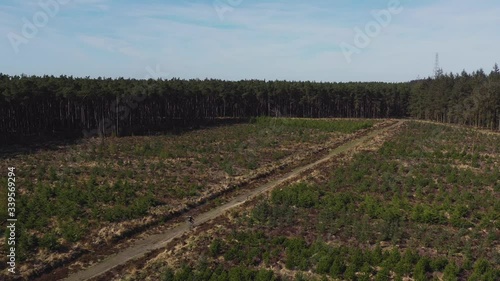 Drone footage of a person mountain biking along an empty country track heading towards a forest on a sunny morning in North Yorkshire England completely isolated photo