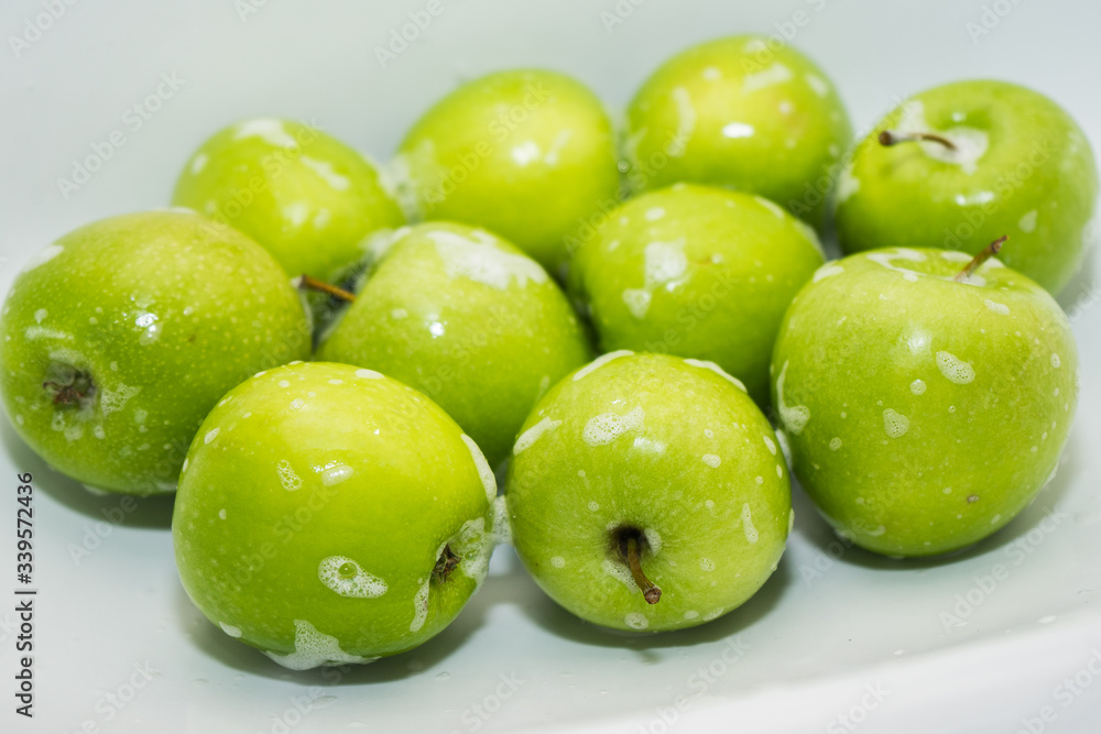 Obraz premium .Washing fruit. Soapy green apples in the sink. Washing fruits and vegetables for the prevention of coronavirus covid-19 2019-ncov