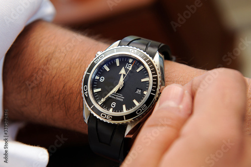 man's hand winding a classic wrist watch passing the time photo