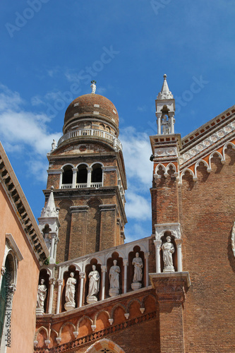 Detail of the facade and bell tower of the church of the Madonna dell'Orto in Venice. The building is in Venetian Gothic style, made of brick with decorative elements in stone and marble. Italy.