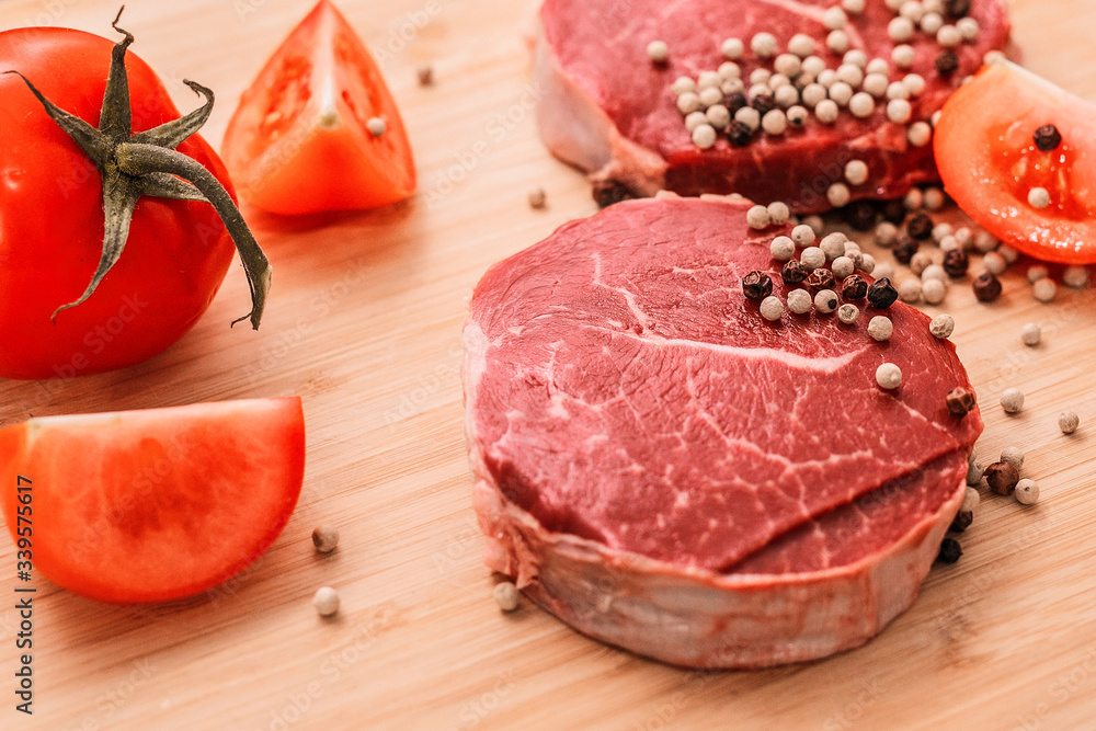 raw meat lies on a board with black pepper and tomatoes raw meat lies on a board with black pepper and tomatoes