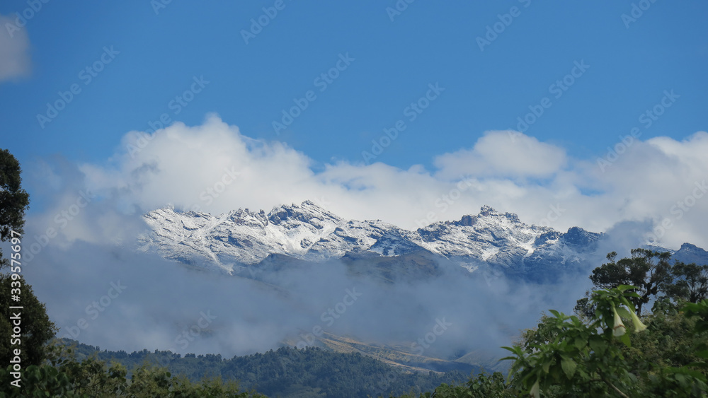 Snow-capped mountain peaks with light white clouds