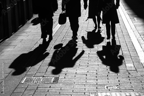 Shadows of city workers walking through alley in bright sunlight 