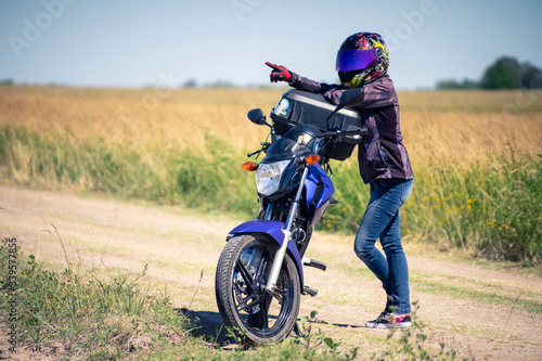 Mujer motociclista sola en el campo con su motocicleta