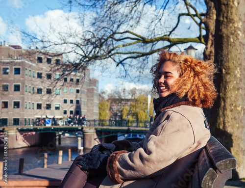 Canvas Print young pretty african american girl with curly hair at water channel in Amsterdam