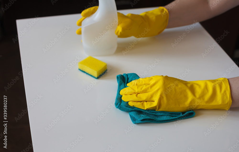 Cleaning kitchen. Disinfection at home. Hands in rubber gloves holding spray cleaner and duster.