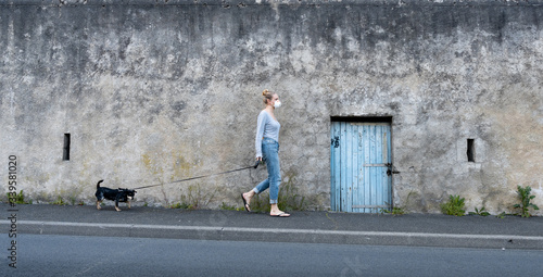 Blonde French woman wearing mask walking dog amid coronavirus outbreak