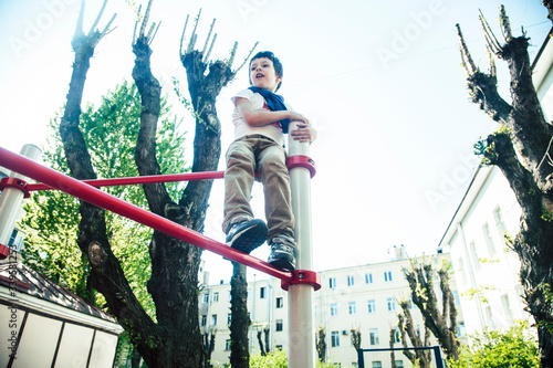 little cute blond boy hanging on playground outside, alone training with fun, lifestyle children concept