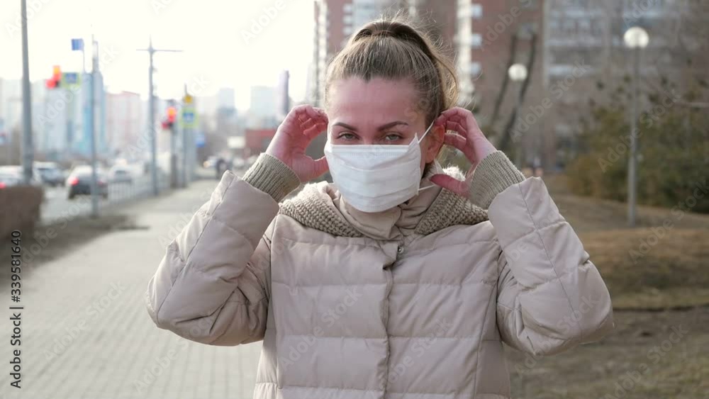 Woman in a medical mask. Portrait of a woman on a city street. She puts on a protective medical mask. Woman in a medical mask. Portrait of a woman on a city street. She puts on a protective medical mask.