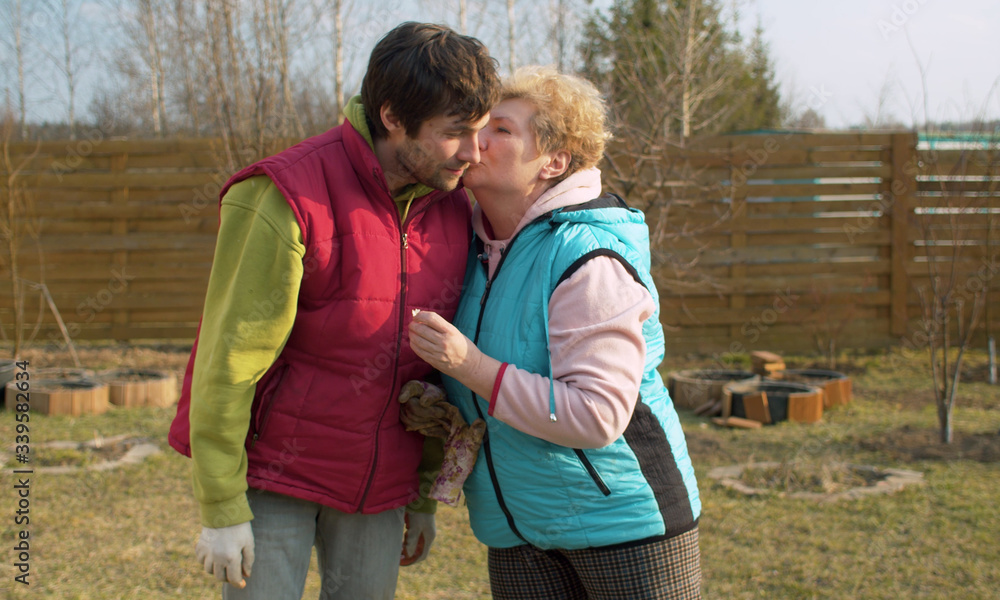 Mom and son in the garden in spring. Mother hugging and kissing her son. Mothers day, family relations concept Mom and son in the garden in spring. Mother hugging and kissing her son. Mothers day, family relations concept