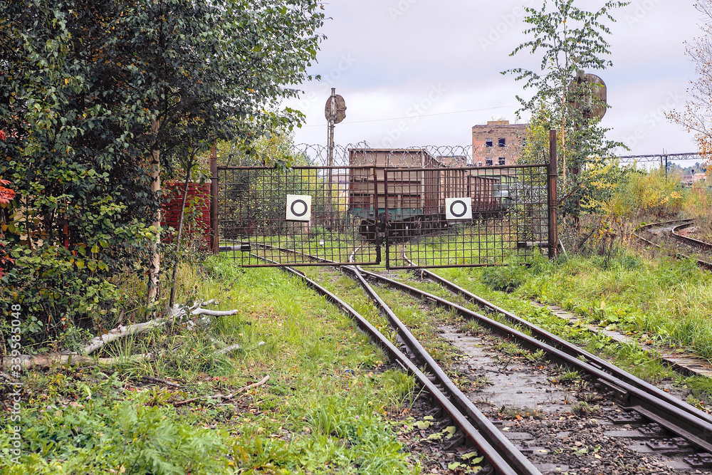 Obraz premium The the railway track abuts against closed lattice metal gates, behind which the rails diverge in two different directions
