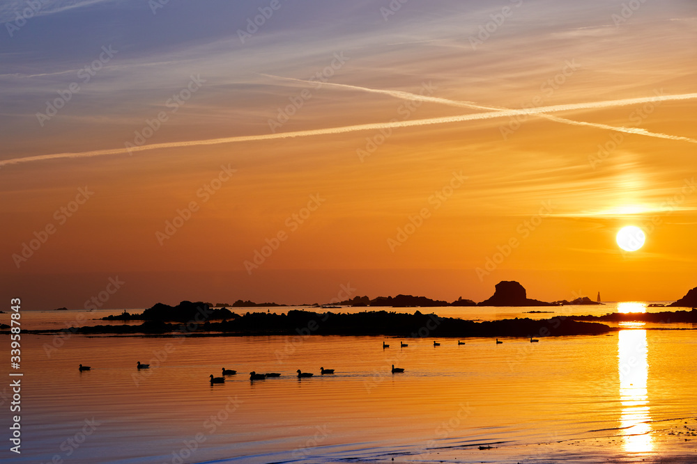 Sunset at St Clements Bay, Jersey CI with smooth sea, rocks, ducks and demi de pas.