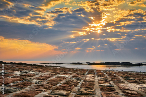 Sunrise at La Rocque harbour  Jersey CI  with the stone slip in the foreground and cloudy sky. Selective focus.