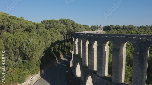 Ancient Pegoes aqueduct near Tomar, Portugal at sunset. Drone descends between the aqueduct and trees to the road photo