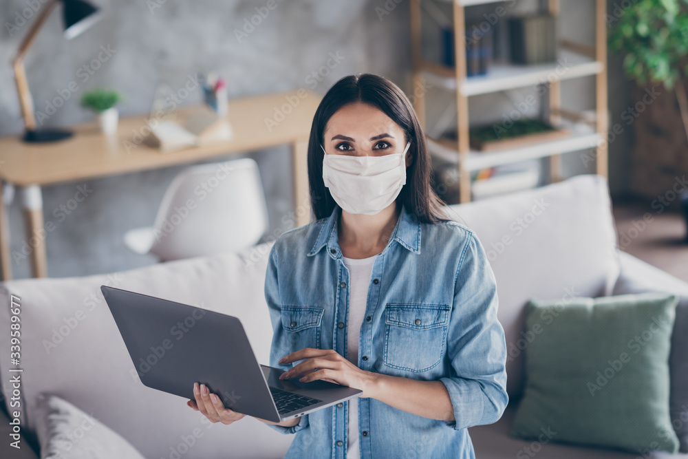 Portrait of positive girl self quarantine corona virus infection work home office use laptop wear medical mask jeans shirt in house indoors Portrait of positive girl self quarantine corona virus infection work home office use laptop wear medical mask jeans shirt in house indoors