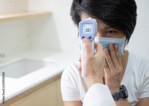 Woman doctor holding medical infrared forehead thermometer checking body temperature of coronavirus infected patients in quarantine area, showing high fever. Covid-19 and coronavirus concept.