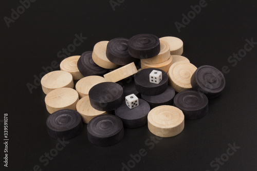 Backgammon. Board game. White dice and white and black chips for playing on a black background. Game for recreation