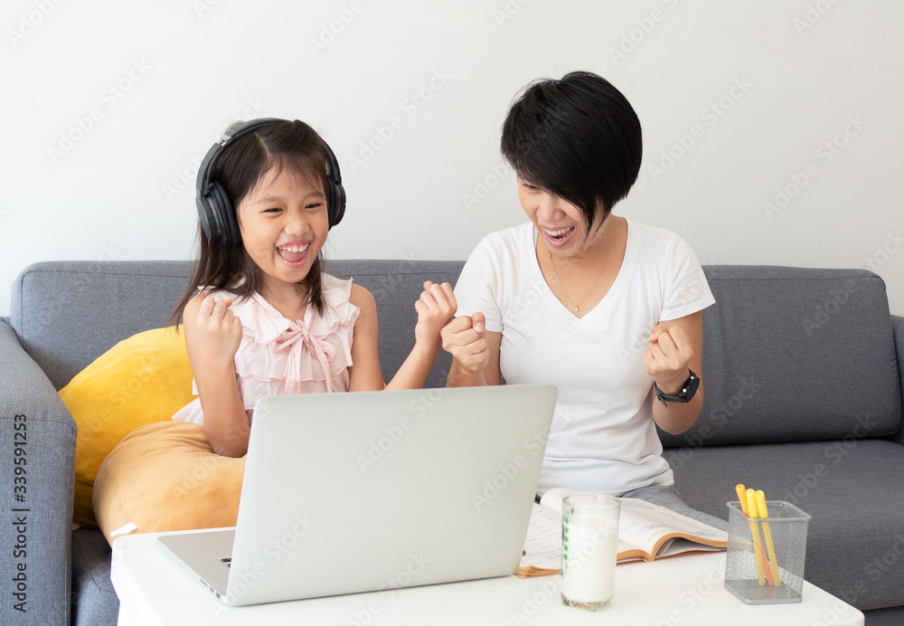Cute asian girl and her teacher use notebook for studying online lesson during home quarantine. Online education, study at home, home school, social distance, coronavirus and covid-19 concept. Cute asian girl and her teacher use notebook for studying online lesson during home quarantine. Online education, study at home, home school, social distance, coronavirus and covid-19 concept.