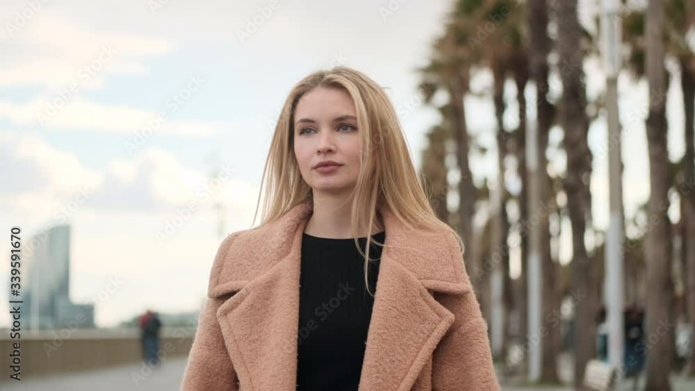 Handheld tracking shot of beautiful blond girl in coat walking through city street Handheld tracking shot of beautiful blond girl in coat walking through city street