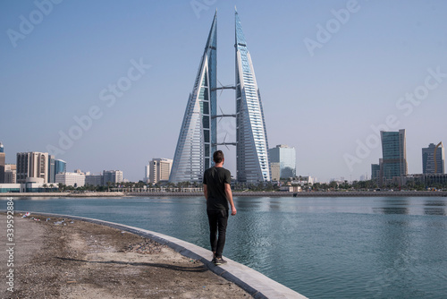 Photography young male traveler walking towards skyscraper in manama bahrain