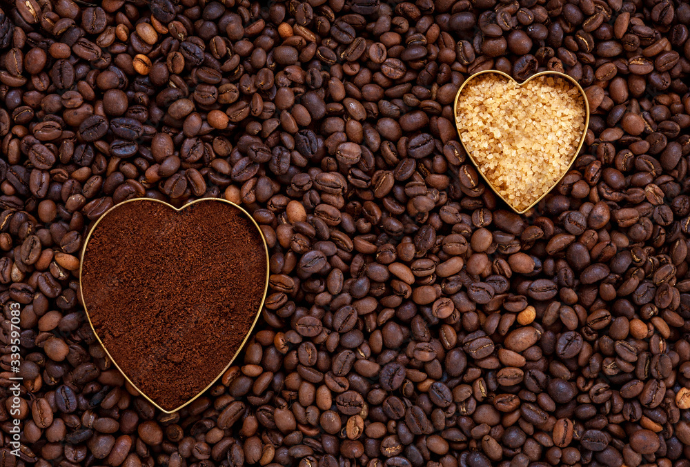 Heart shaped fresh ground coffee and cane sugar on coffee beans background Heart shaped fresh ground coffee and cane sugar on coffee beans background