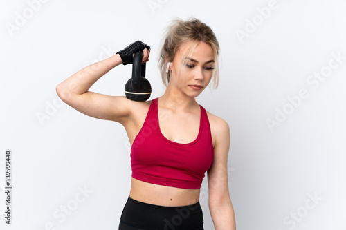 Teenager girl holding waffles over isolated blue background making weightlifting with kettlebell © luismolinero
