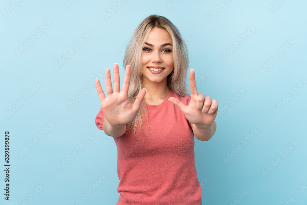 Fototapeta premium Teenager girl over isolated blue background counting seven with fingers