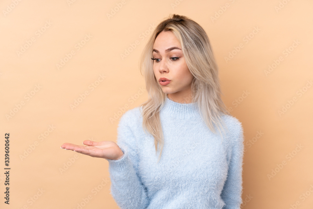 Teenager girl over isolated background holding copyspace imaginary on the palm Teenager girl over isolated background holding copyspace imaginary on the palm