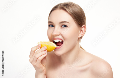 Young attractive girl posing at studio with lemon. Beautiful female face with healthy skin and eyes. Young blonde natural woman with vivid makeup. Skin care