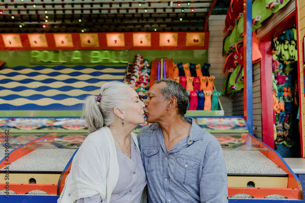 Obraz premium Happy senior couple kissing in a theme park